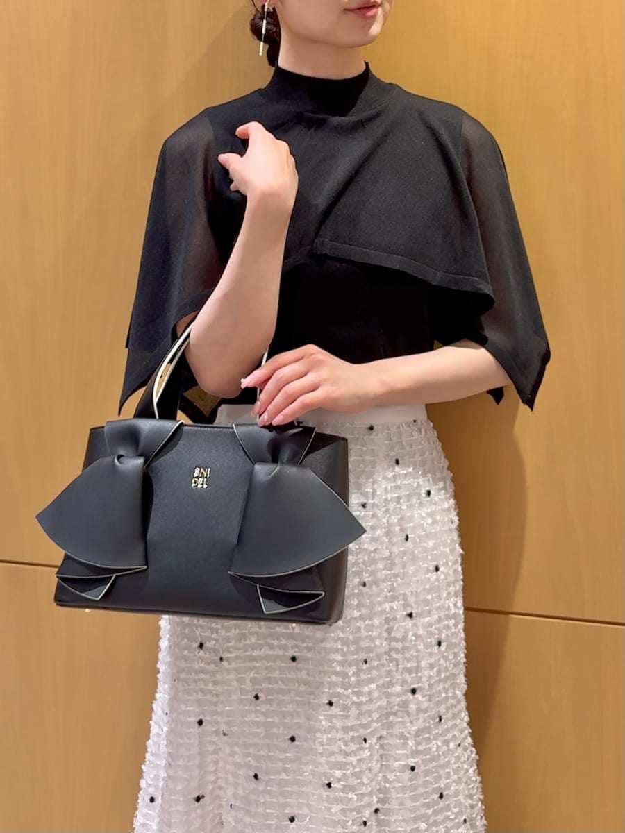 ブラック系のパンプス、ブラック系のハンドバッグ、その他のイヤリングを着用したレディースの春コーディネートの7枚目の写真