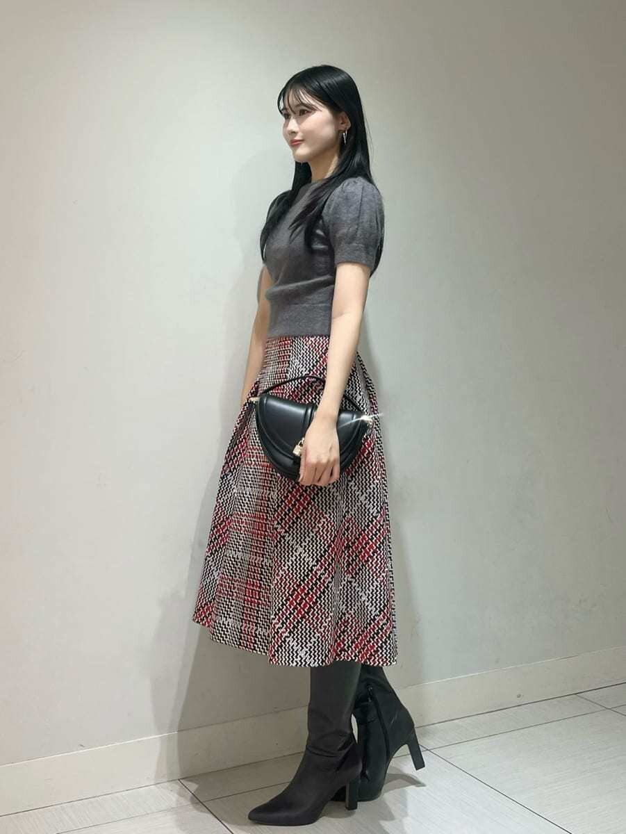 グレー系のニット/セーター、レッド系のスカート、ブラック系のハンドバッグを着用したレディースの秋コーディネートの2枚目の写真