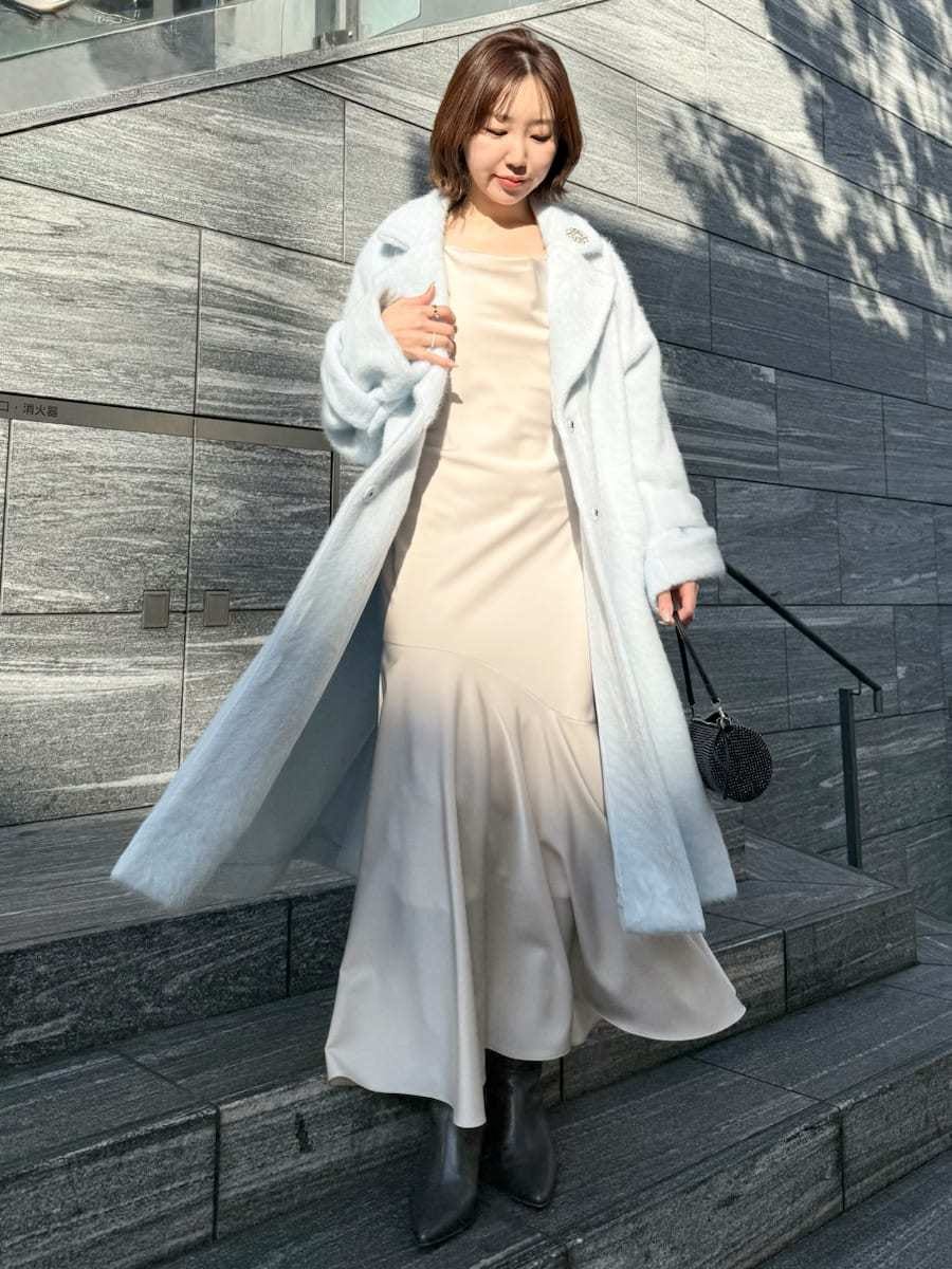 ブルー系のチェスターコート、ホワイト系のワンピースを着用したレディースの冬コーディネートの3枚目の写真