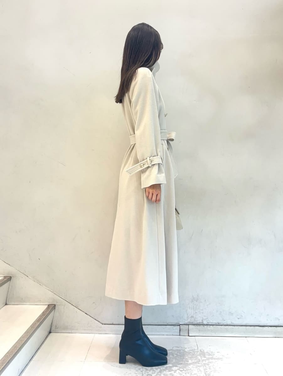 ホワイト系のチェスターコート、ベージュ系のワンピース、ホワイト系のボストンバッグを着用したレディースの秋コーディネートの6枚目の写真