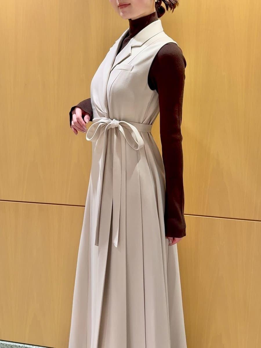 ピンク系のステンカラーコート、ベージュ系のワンピース、ブラウン系のニット/セーターを着用したレディースの秋コーディネートの8枚目の写真