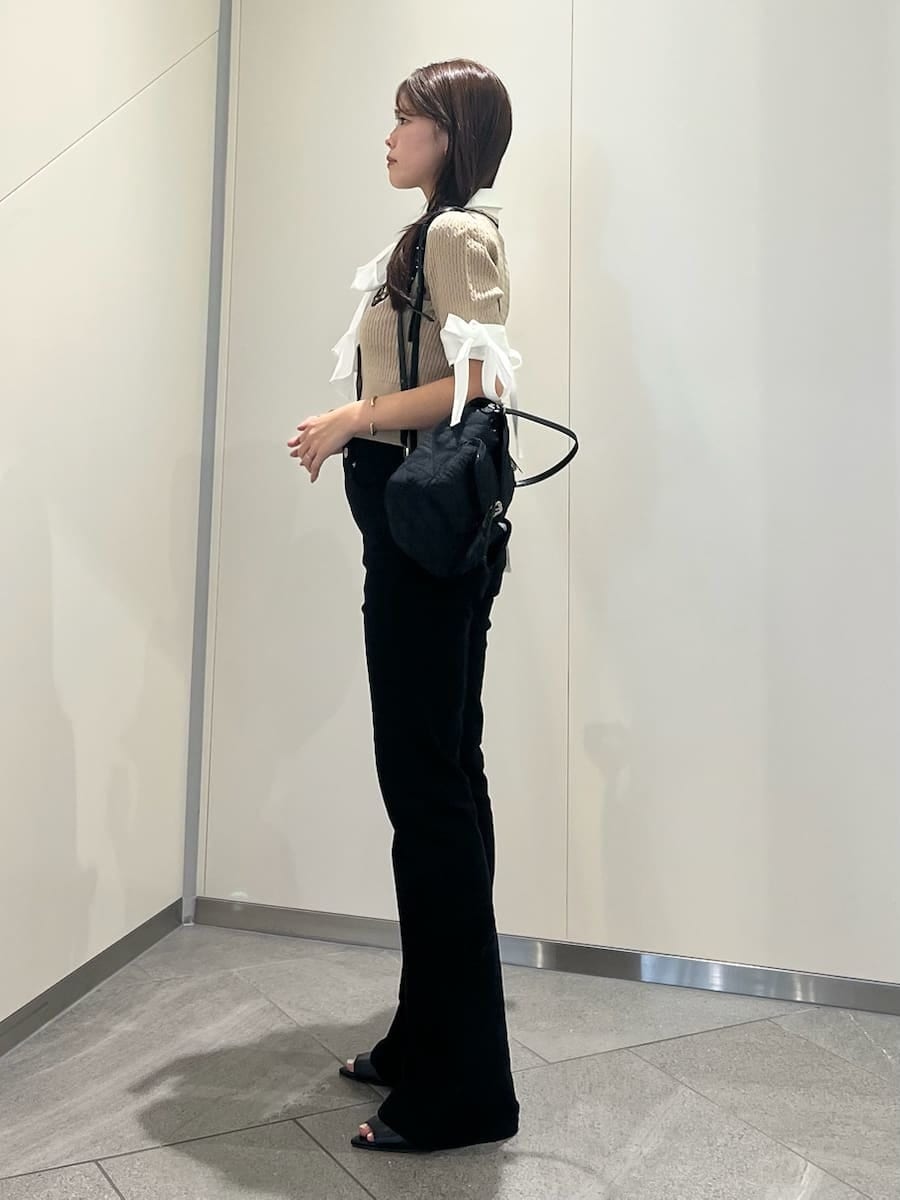ブラック系のデニムパンツ、ベージュ系のニット/セーター、ブラック系のサンダルを着用したレディースの夏コーディネートの2枚目の写真