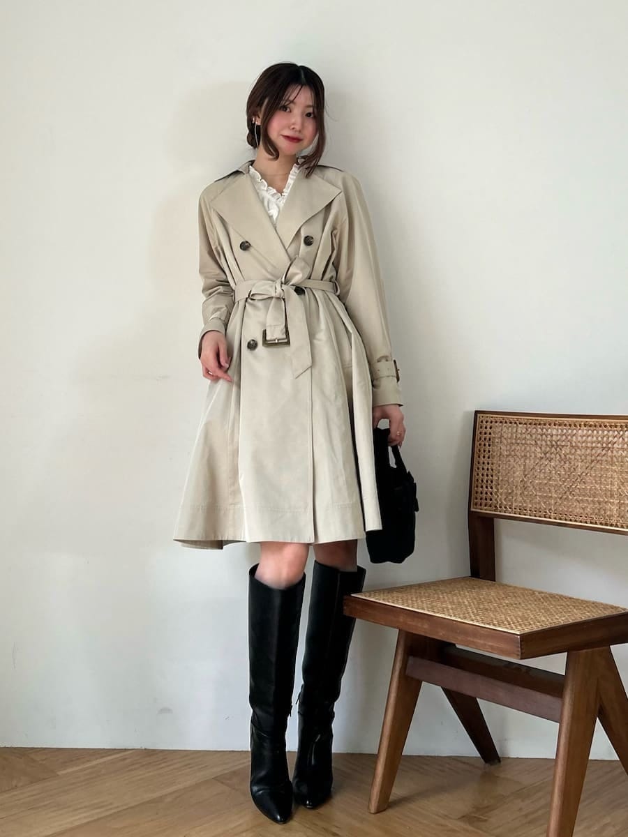 ブラック系のブーツ、ホワイト系のその他トップス、ベージュ系のトレンチコートを着用したレディースの春コーディネートの2枚目の写真