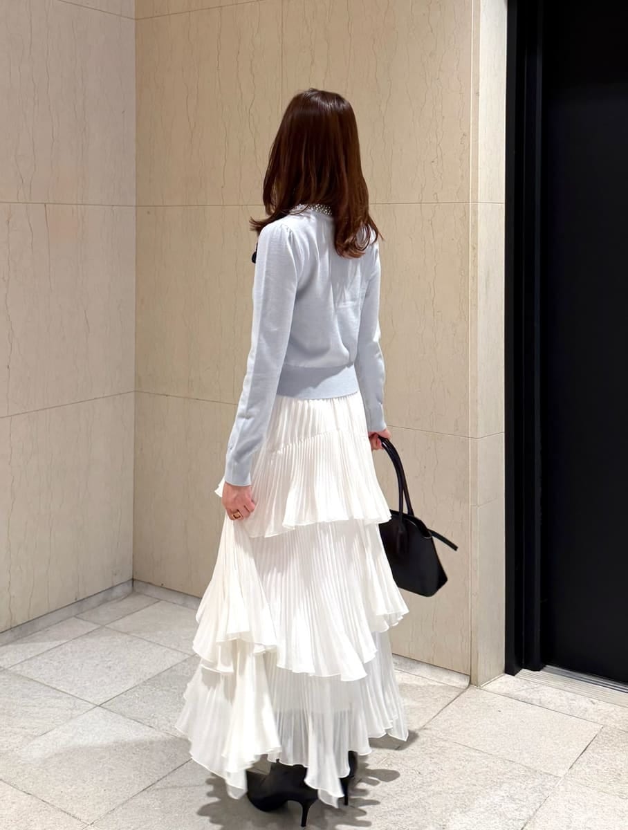 ホワイト系のスカート、ブラック系のブーツ、ブラック系のボストンバッグを着用したレディースの秋コーディネートの4枚目の写真