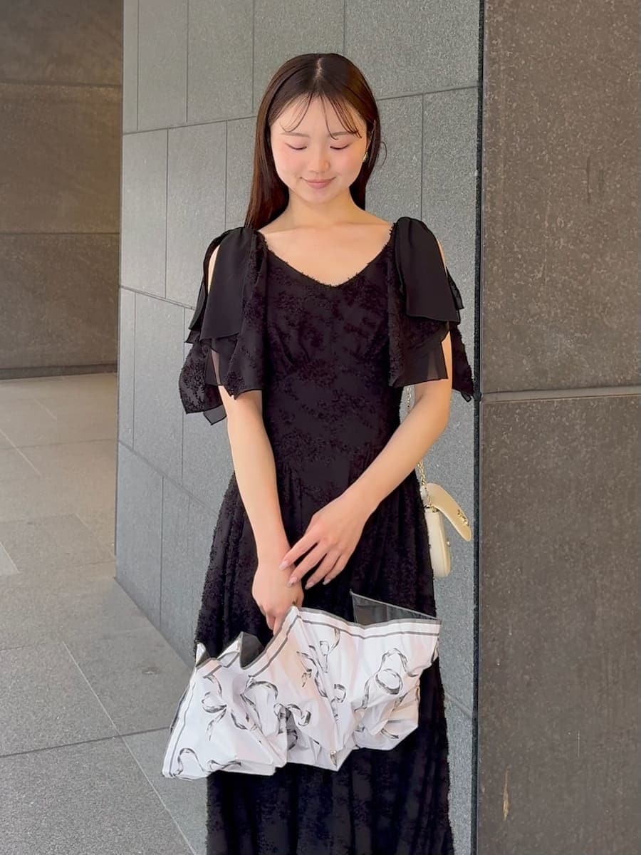 ブラック系のワンピース、ホワイト系のショルダーバッグ、ホワイト系の折りたたみ傘を着用したレディースの春コーディネートの5枚目の写真