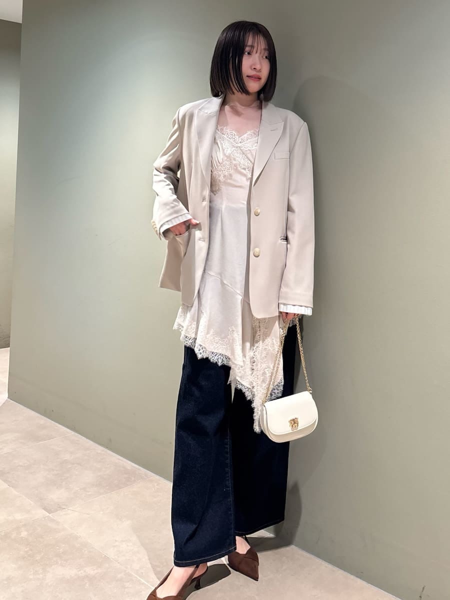 ベージュ系のテーラードジャケット、ブルー系のデニムパンツ、ホワイト系のキャミソールを着用したレディースの春コーディネートの3枚目の写真