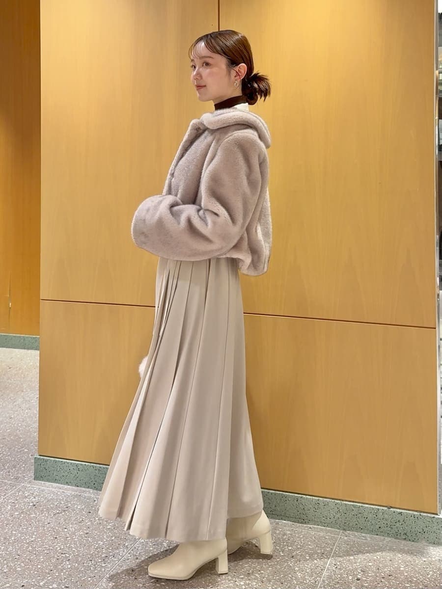 ピンク系のステンカラーコート、ベージュ系のワンピース、ブラウン系のニット/セーターを着用したレディースの秋コーディネートの2枚目の写真