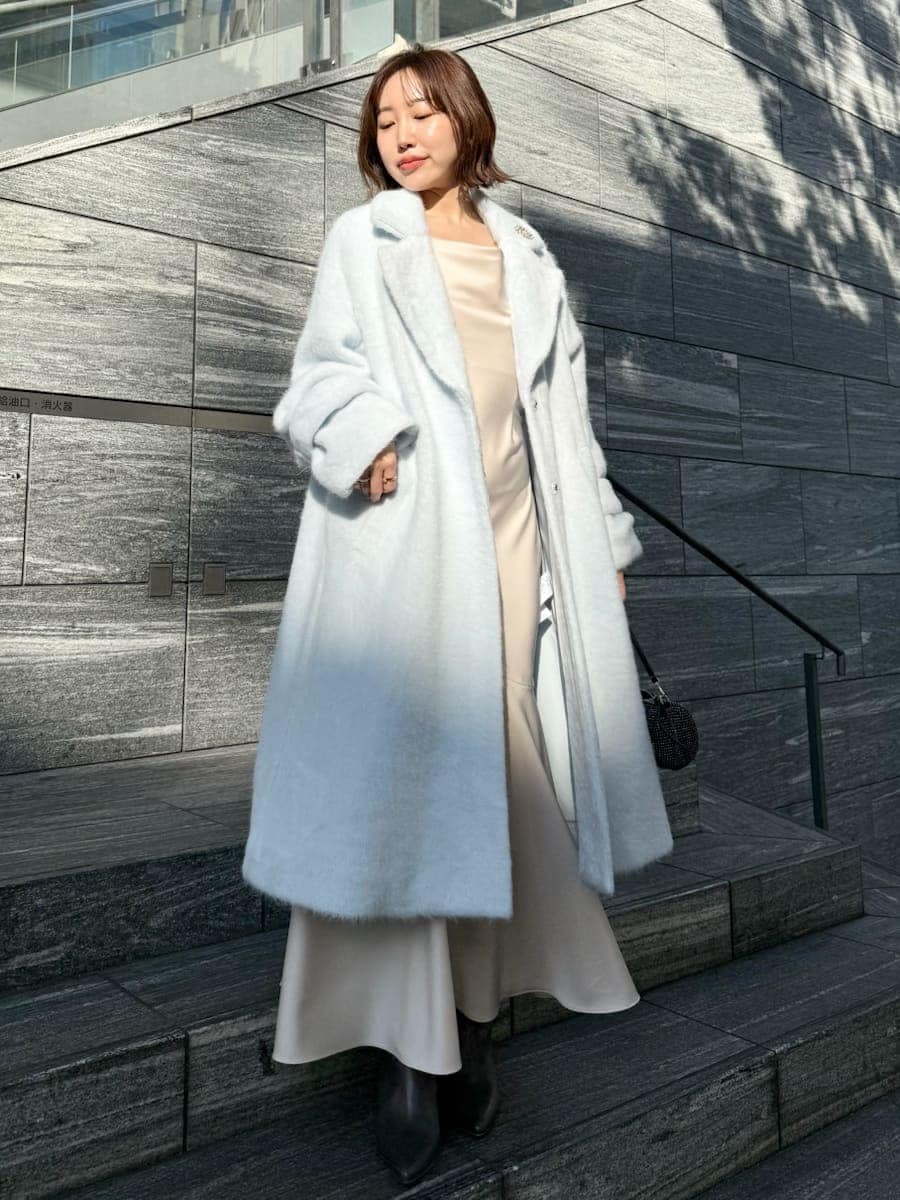ブルー系のチェスターコート、ホワイト系のワンピースを着用したレディースの冬コーディネートの9枚目の写真