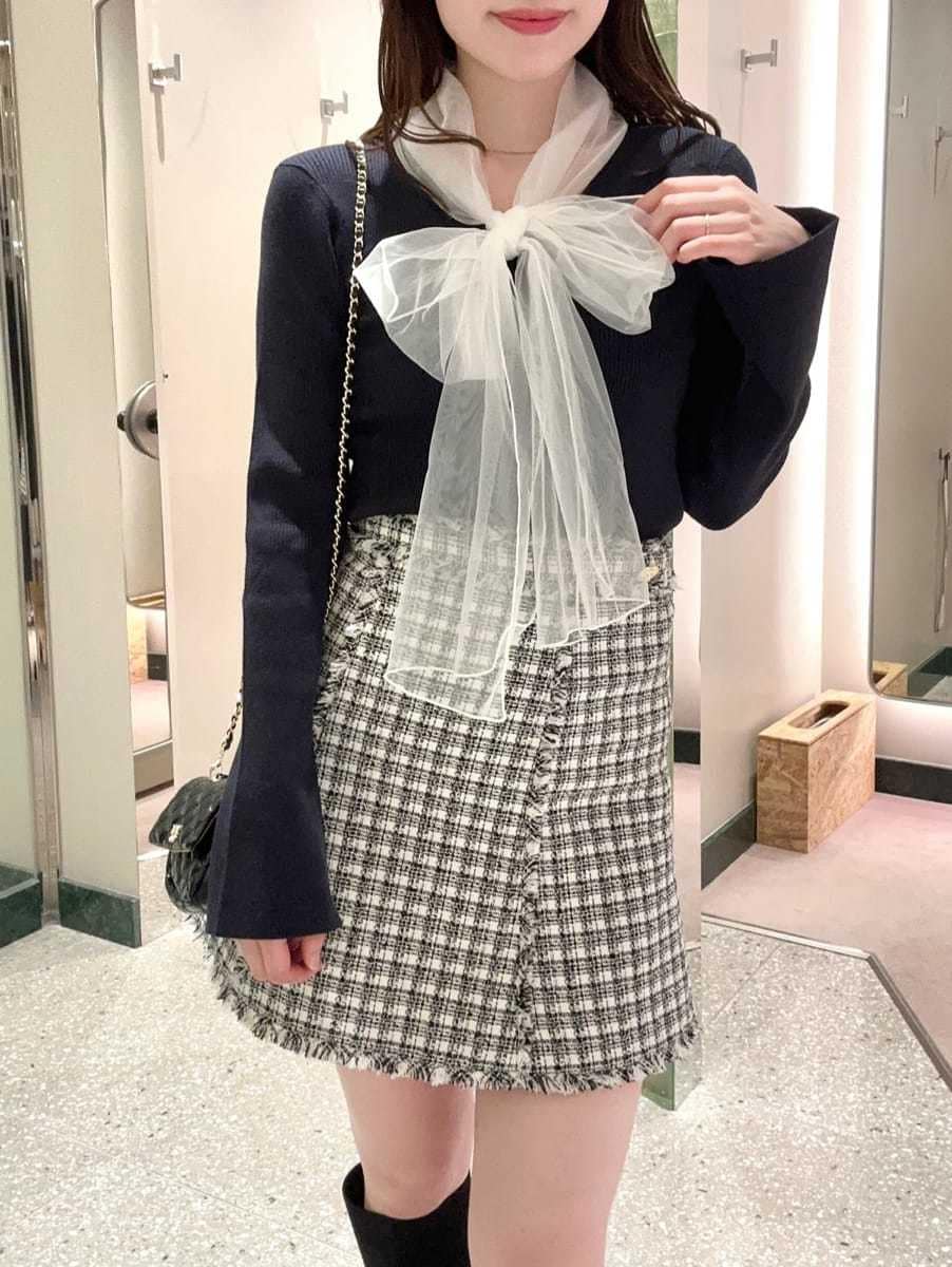 ブルー系のニット/セーター、ホワイト系のスカート、ブラック系のショルダーバッグを着用したレディースの秋コーディネートの3枚目の写真