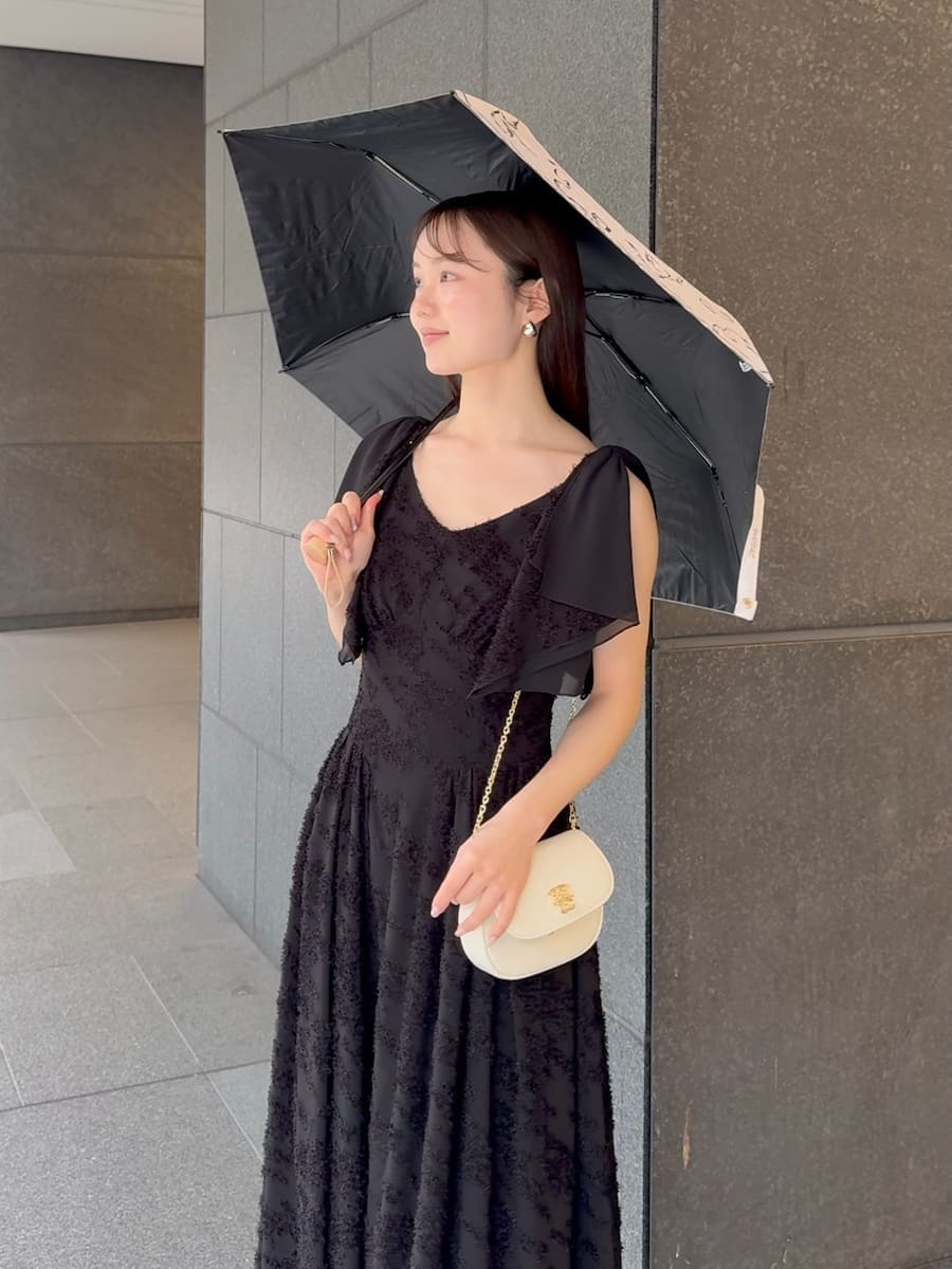 ブラック系のワンピース、ホワイト系のショルダーバッグ、ホワイト系の折りたたみ傘を着用したレディースの春コーディネートの6枚目の写真