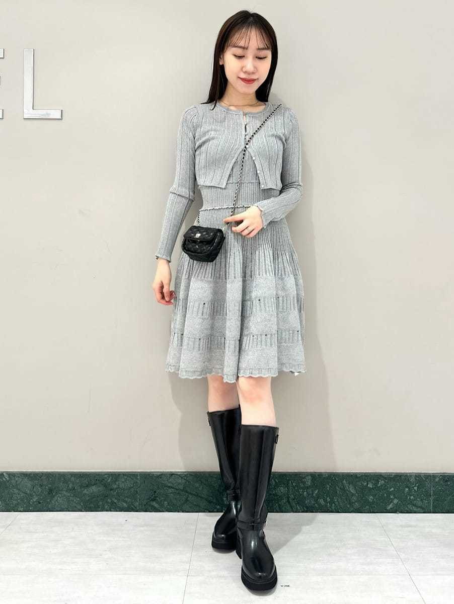 グレー系のステンカラーコート、ブラック系のブーツ、ブラック系のショルダーバッグを着用したレディースの秋コーディネートの2枚目の写真