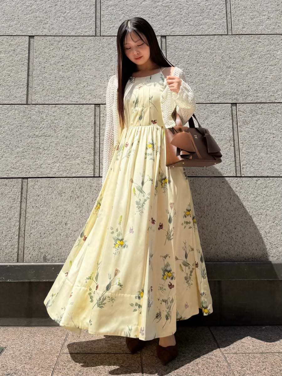 イエロー系のワンピース、ホワイト系のカーディガン/ボレロ、ブラウン系のパンプスを着用したレディースの春コーディネートの2枚目の写真