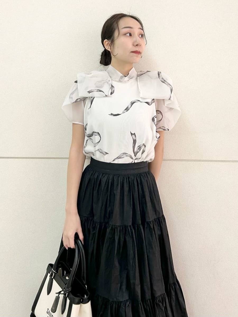 ブラック系のスカート、ブラック系のパンプス、ホワイト系のハンドバッグを着用したレディースの春コーディネートの5枚目の写真