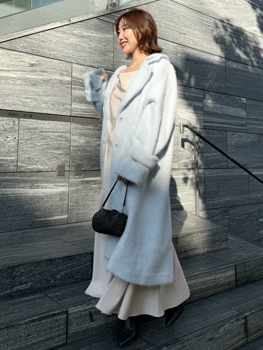 ブルー系のチェスターコート、ホワイト系のワンピースを着用したレディースの冬コーディネートの2枚目の写真
