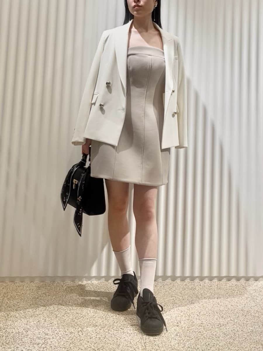 ホワイト系のテーラードジャケット、グリーン系のワンピース、ブラック系のハンドバッグを着用したレディースの冬コーディネートの3枚目の写真