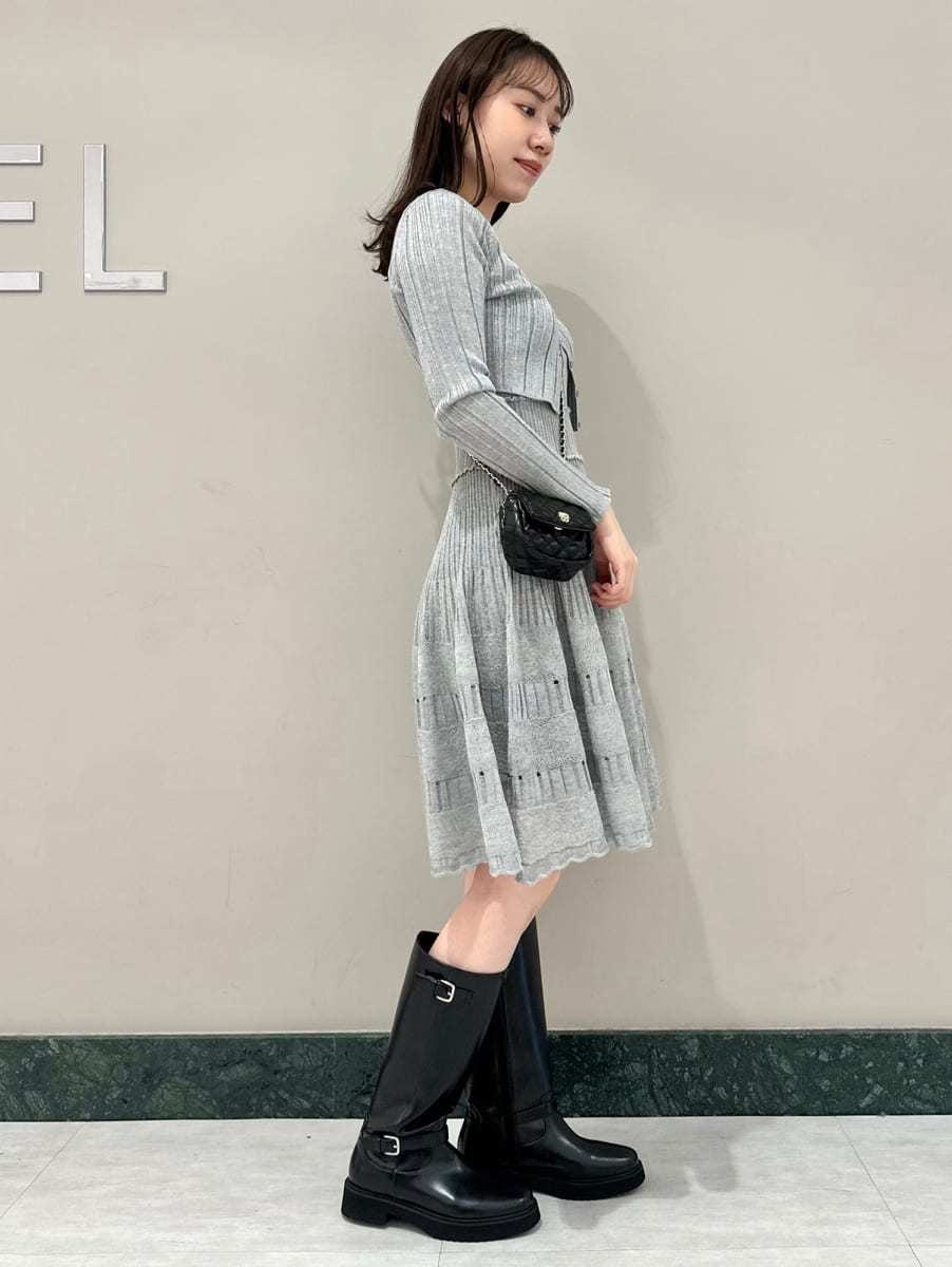 グレー系のステンカラーコート、ブラック系のブーツ、ブラック系のショルダーバッグを着用したレディースの秋コーディネートの5枚目の写真