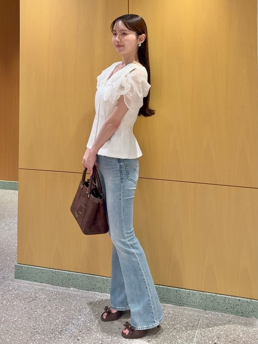 ブルー系のデニムパンツ、ホワイト系のTシャツ/カットソー、ブラウン系のハンドバッグを着用したレディースの夏コーディネートの2枚目の写真