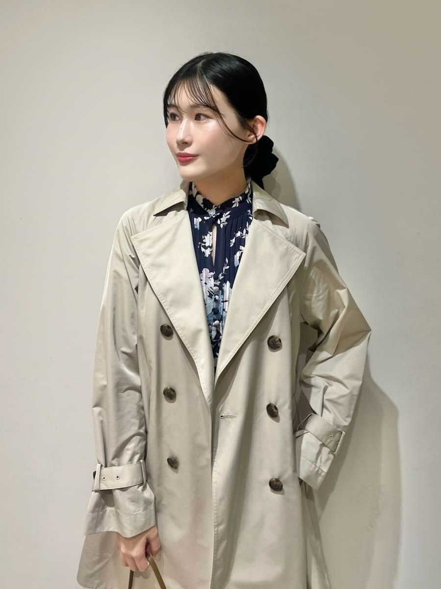ベージュ系のトレンチコート、ブルー系のワンピース、ブラウン系のハンドバッグを着用したレディースの春コーディネートの3枚目の写真