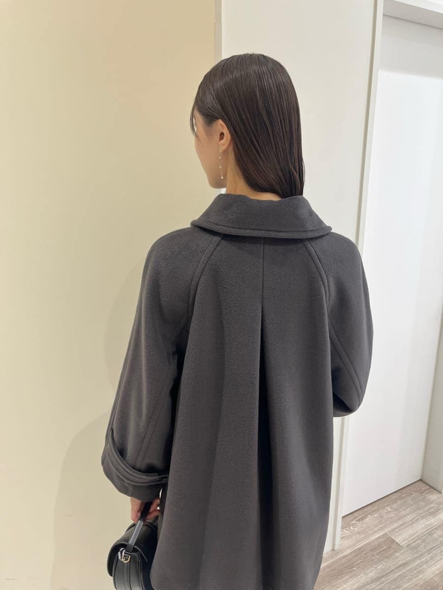 グレー系のステンカラーコート、レッド系のニット/セーター、ブルー系のデニムパンツを着用したレディースの秋コーディネートの4枚目の写真