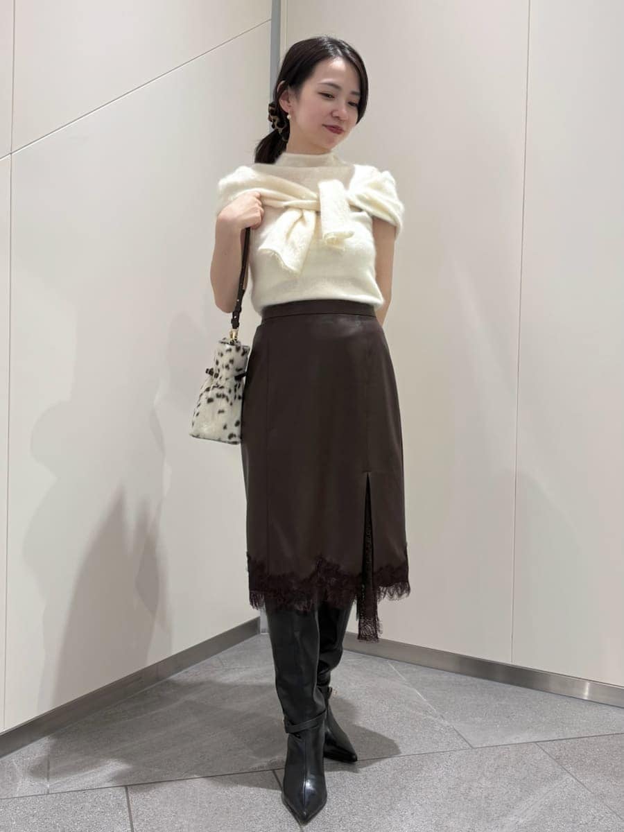 ブラウン系のスカート、ホワイト系のTシャツ/カットソー、ブラック系のブーツを着用したレディースの秋コーディネートの6枚目の写真