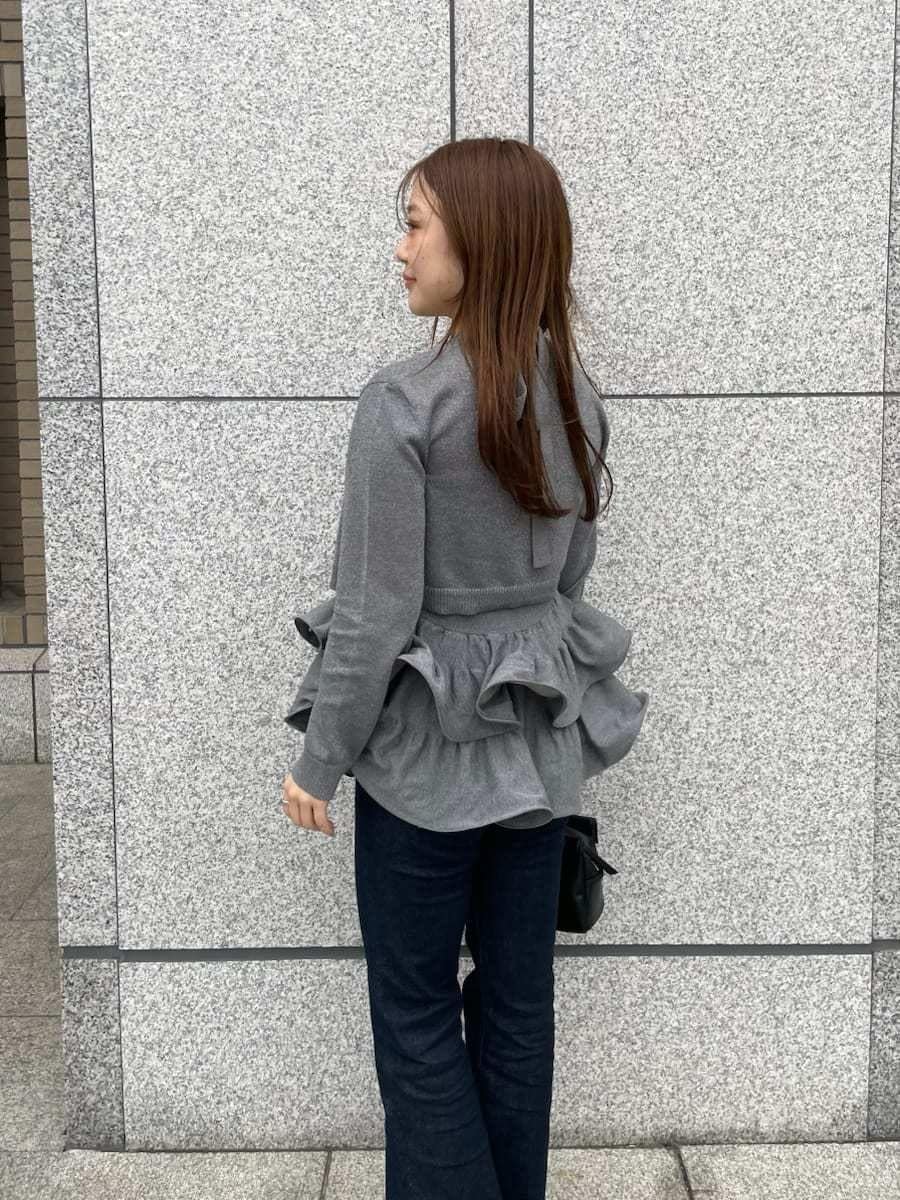 シルバー系のニット/セーター、シルバー系のカーディガン/ボレロ、ブルー系のデニムパンツを着用したレディースの春コーディネートの6枚目の写真