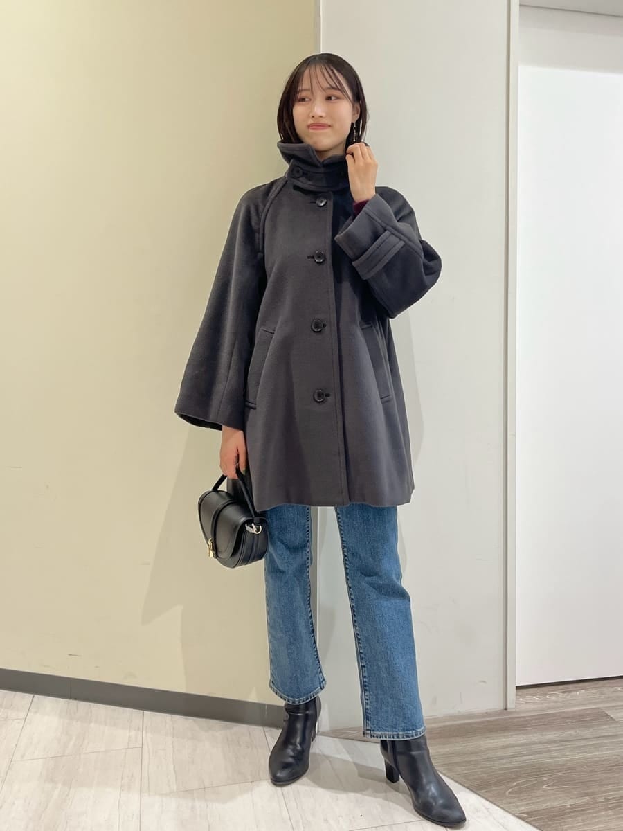 グレー系のステンカラーコート、レッド系のニット/セーター、ブルー系のデニムパンツを着用したレディースの秋コーディネートの6枚目の写真