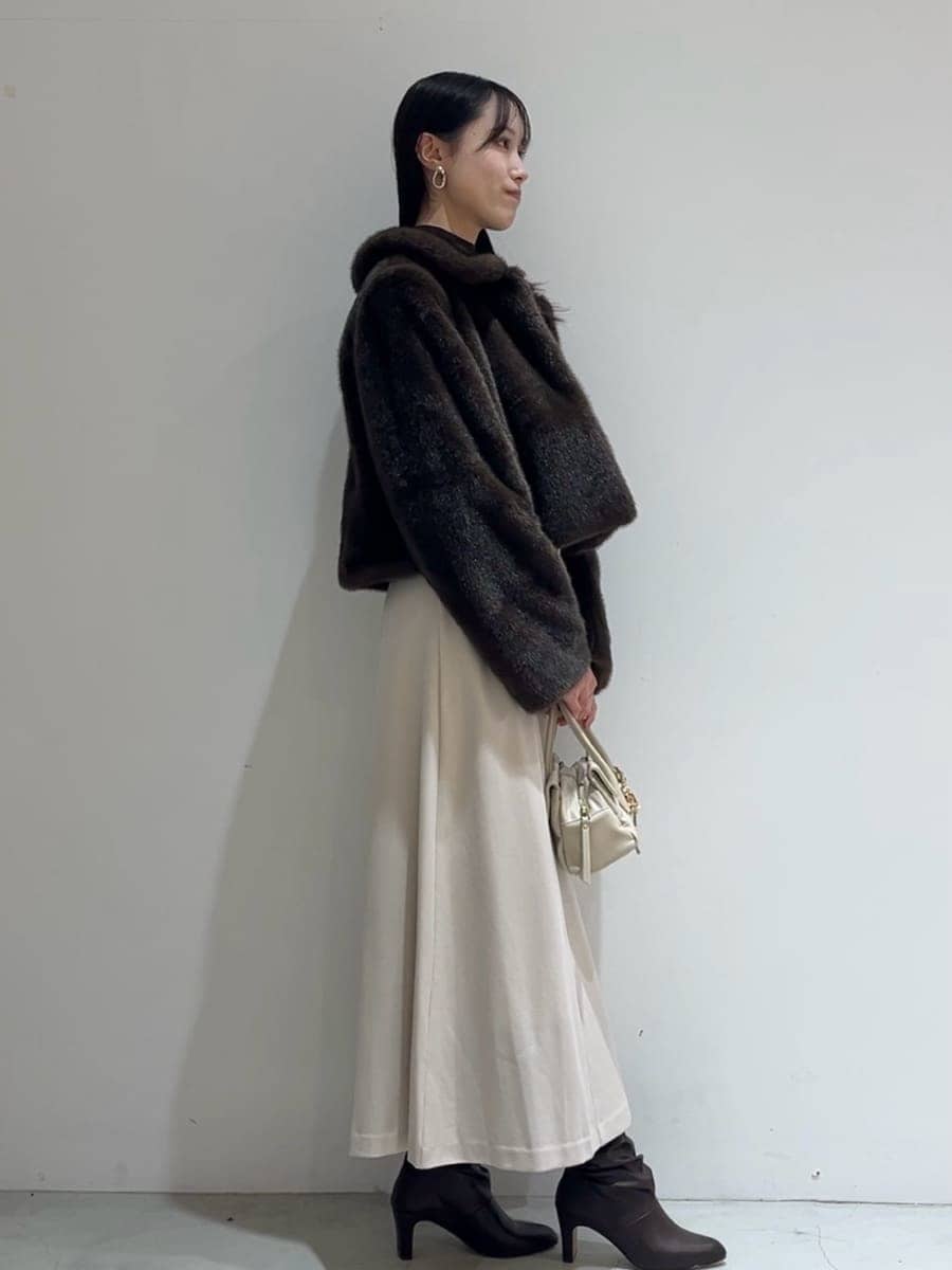 ブラウン系のステンカラーコート、ベージュ系のワンピース、ブラウン系のニット/セーターを着用したレディースの秋コーディネートの2枚目の写真