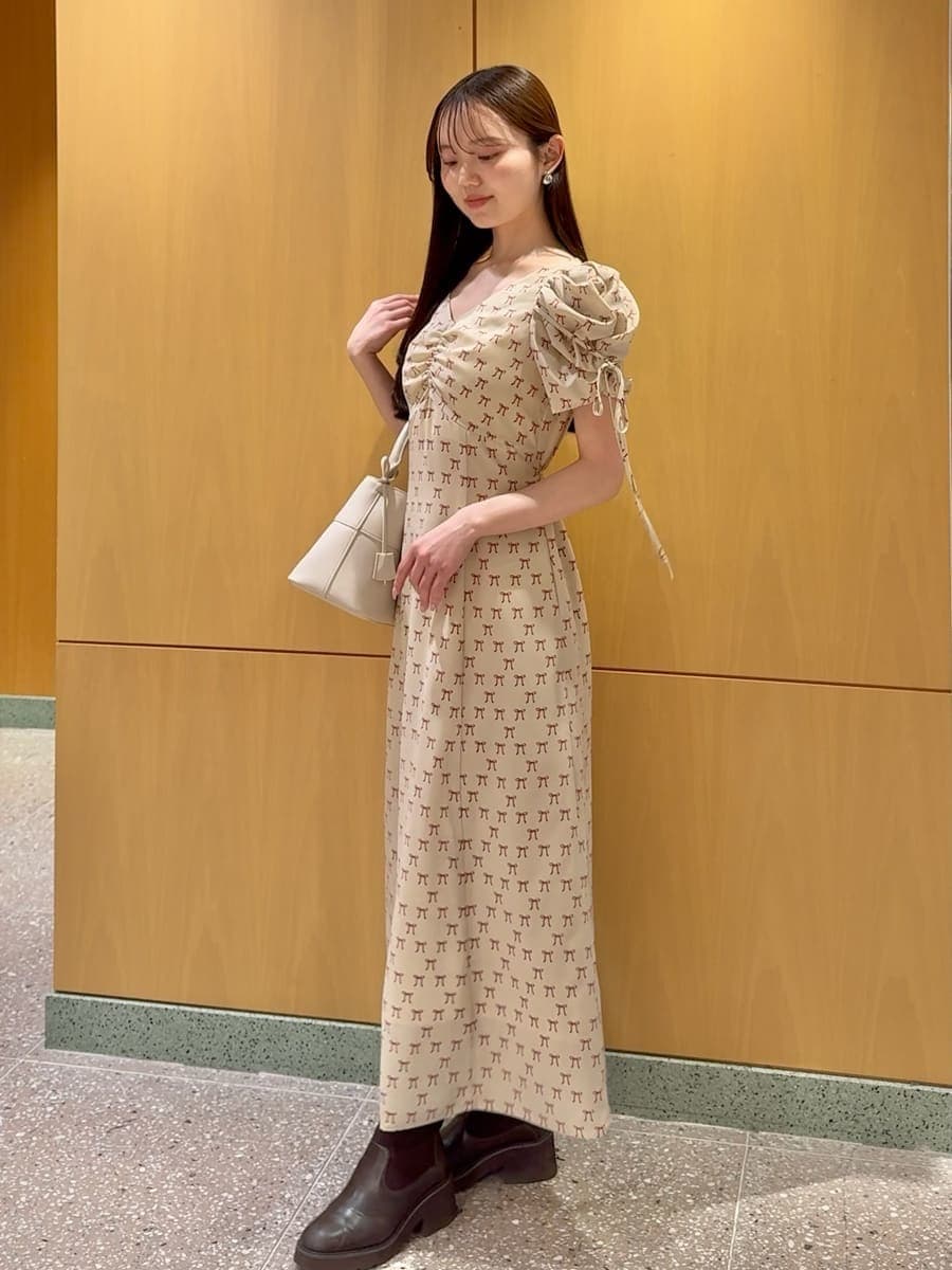 ホワイト系のハンドバッグ、ベージュ系のワンピース、レッド系のカーディガン/ボレロを着用したレディースの冬コーディネートの4枚目の写真