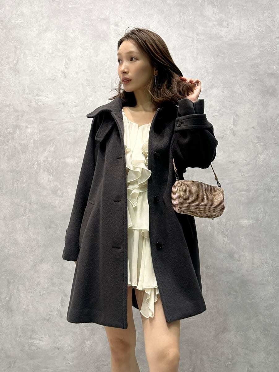 グレー系のステンカラーコート、ホワイト系のワンピースを着用したレディースの秋コーディネートの2枚目の写真