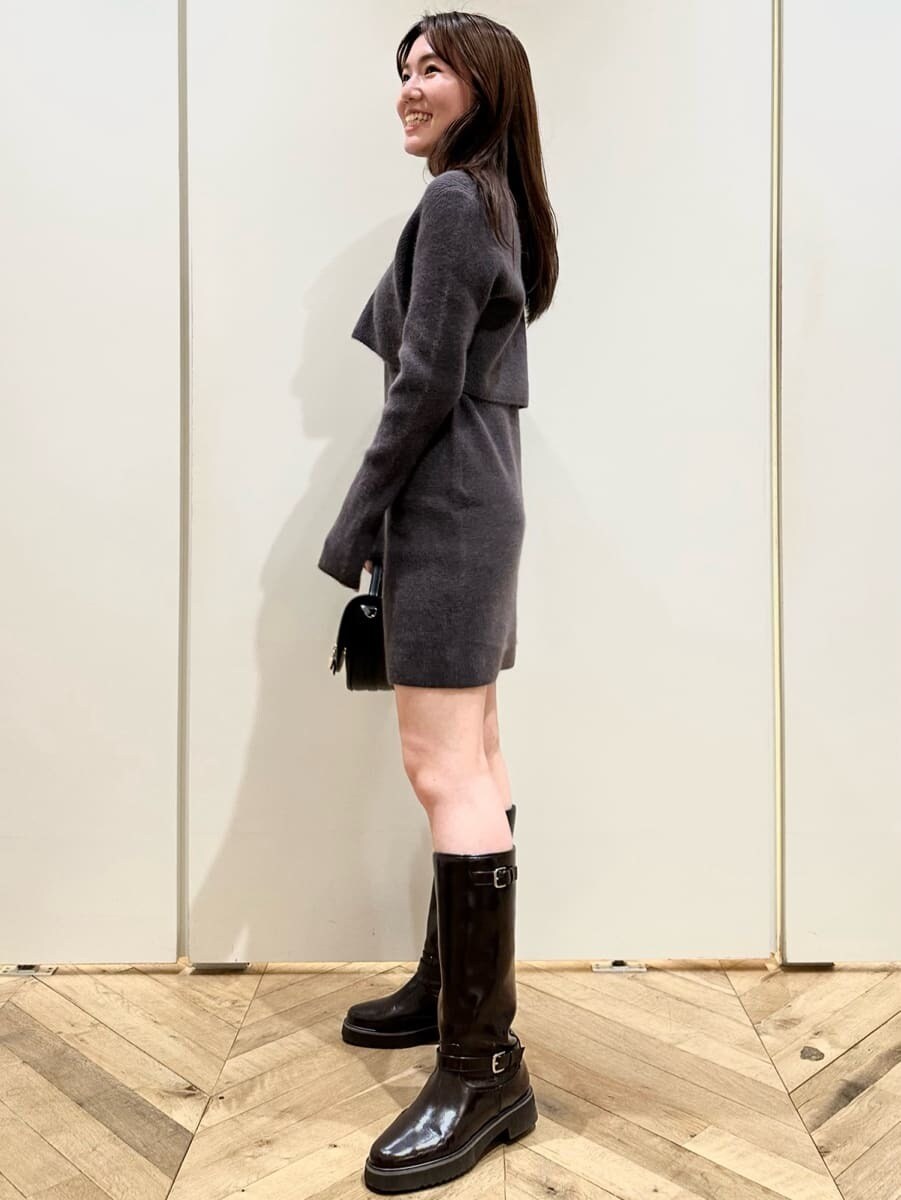 グレー系のカーディガン/ボレロ、グレー系のワンピース、ブラウン系のブーツを着用したレディースの秋コーディネートの2枚目の写真