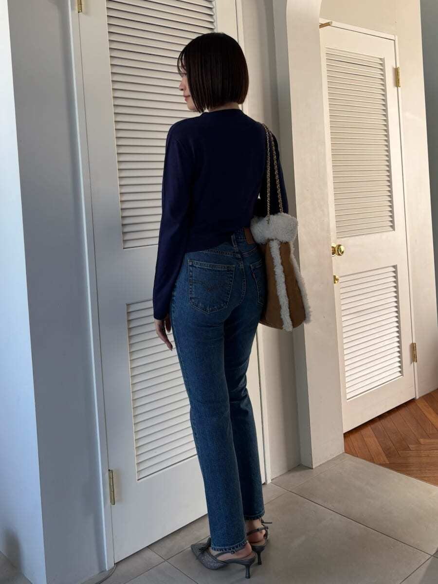 ブルー系のデニムパンツ、ブラウン系のハンドバッグを着用したレディースの秋コーディネートの9枚目の写真