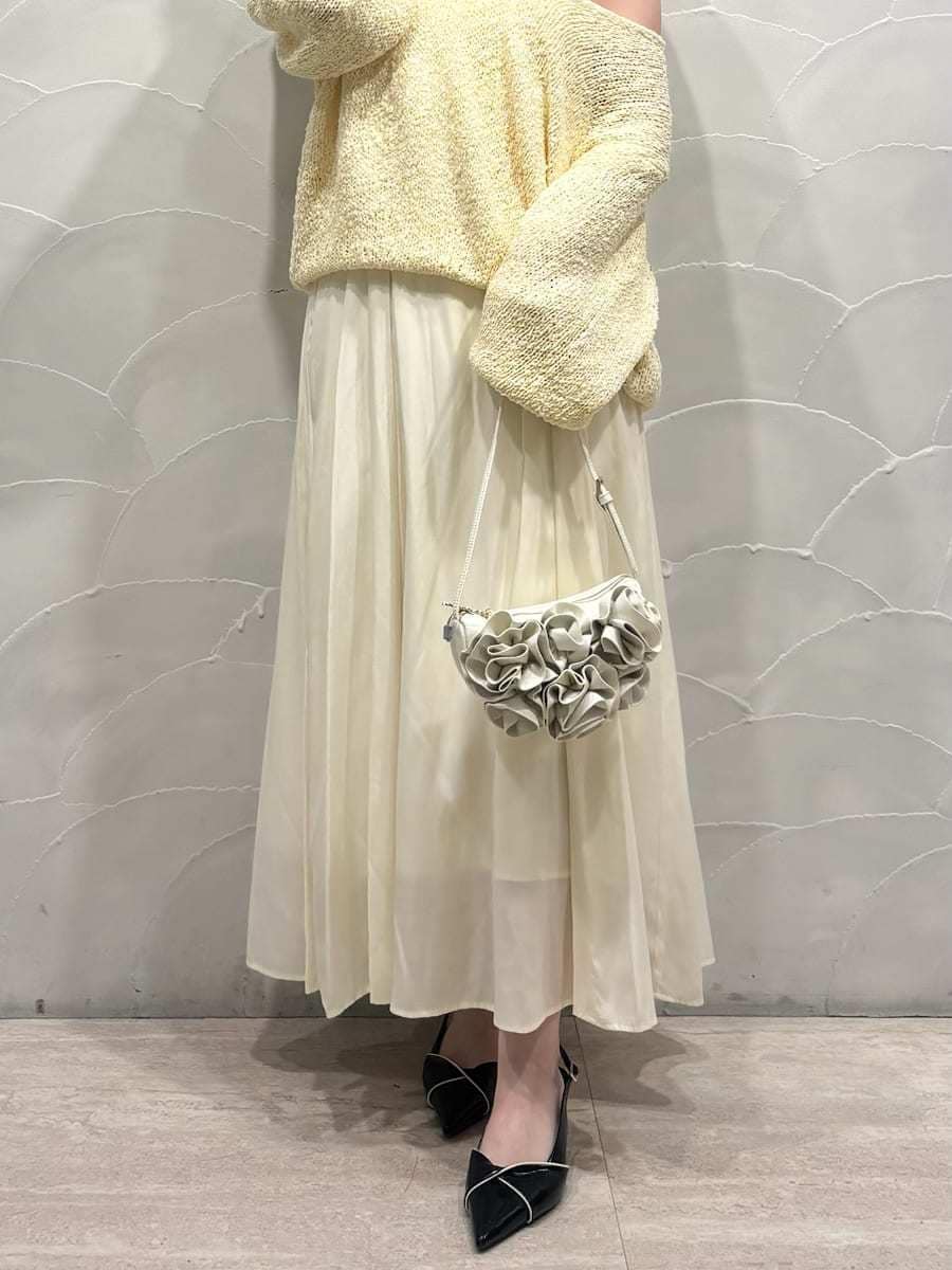 イエロー系のワンピース、ブラック系のパンプス、ホワイト系のハンドバッグを着用したレディースの冬コーディネートの4枚目の写真