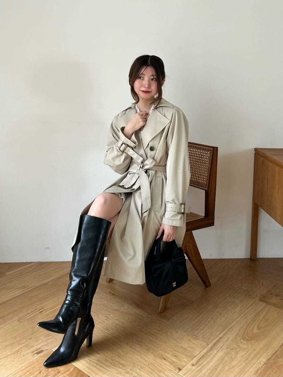 ブラック系のブーツ、ホワイト系のその他トップス、ベージュ系のトレンチコートを着用したレディースの春コーディネートの6枚目の写真