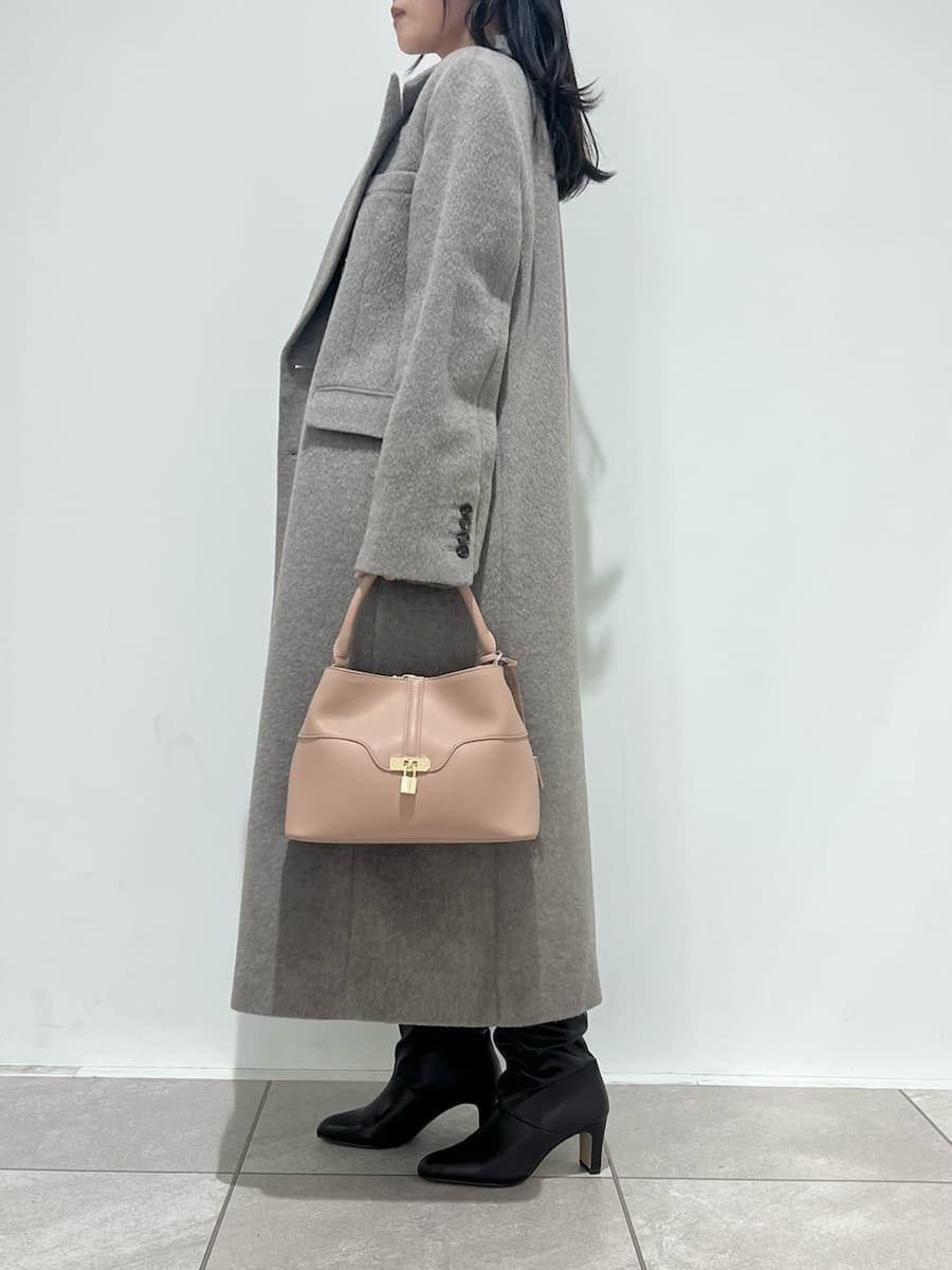 ピンク系のショルダーバッグ、ベージュ系のチェスターコート、ホワイト系のその他パンツを着用したレディースの冬コーディネートの2枚目の写真