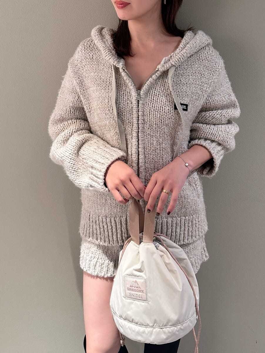 ホワイト系のその他パンツ、ホワイト系のニット/セーター、ベージュ系のハンドバッグを着用したレディースの夏コーディネートの4枚目の写真