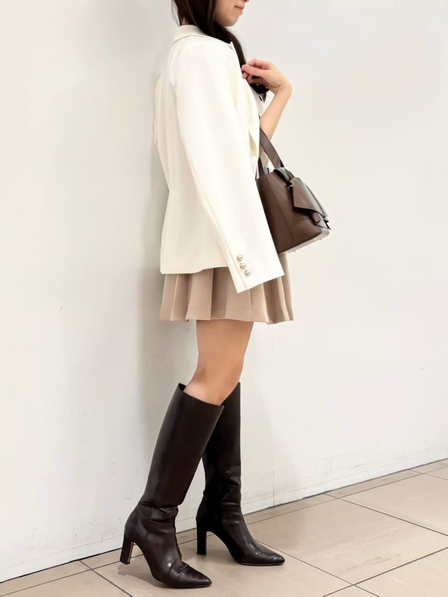 ブラウン系のブーツ、ホワイト系のテーラードジャケット、ベージュ系のスカートを着用したレディースの冬コーディネートの3枚目の写真