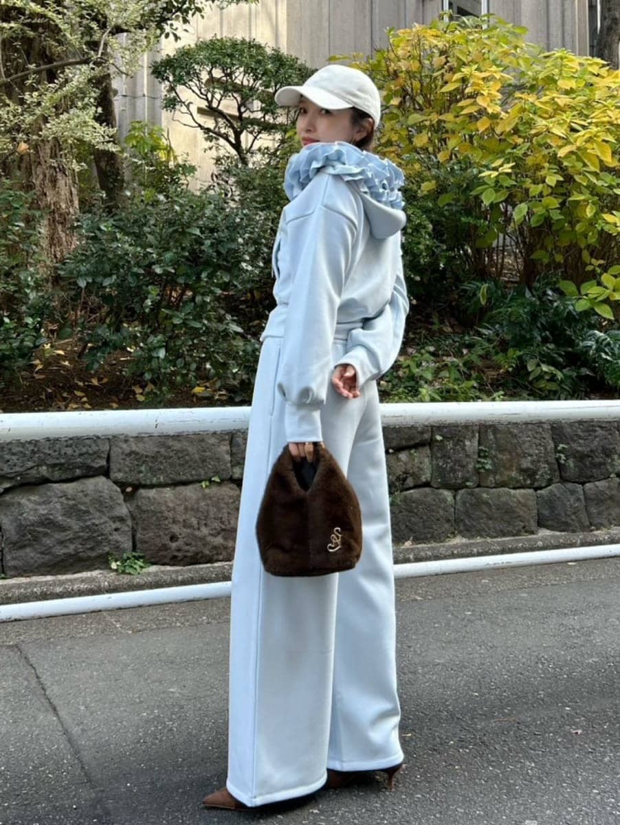 ブラウン系のハンドバッグ、ブルー系のパーカー、ブルー系のスウェットパンツを着用したレディースの冬コーディネートの2枚目の写真