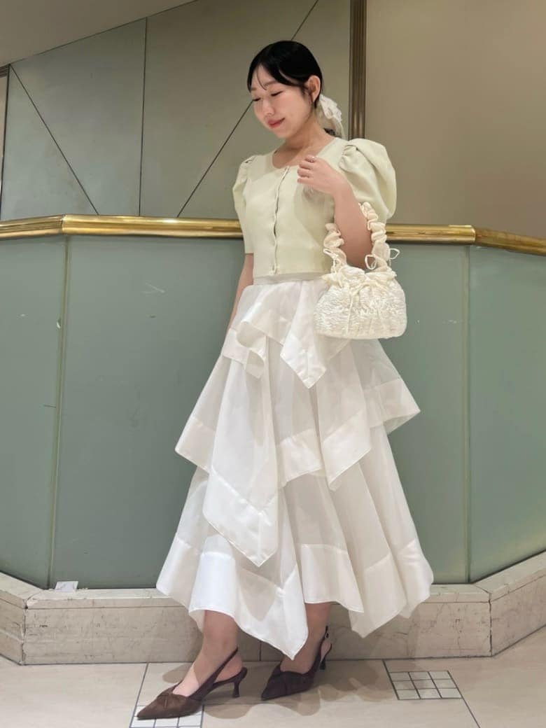 ホワイト系のスカート、イエロー系のカーディガン/ボレロ、ブラウン系のパンプスを着用したレディースの春コーディネートの2枚目の写真