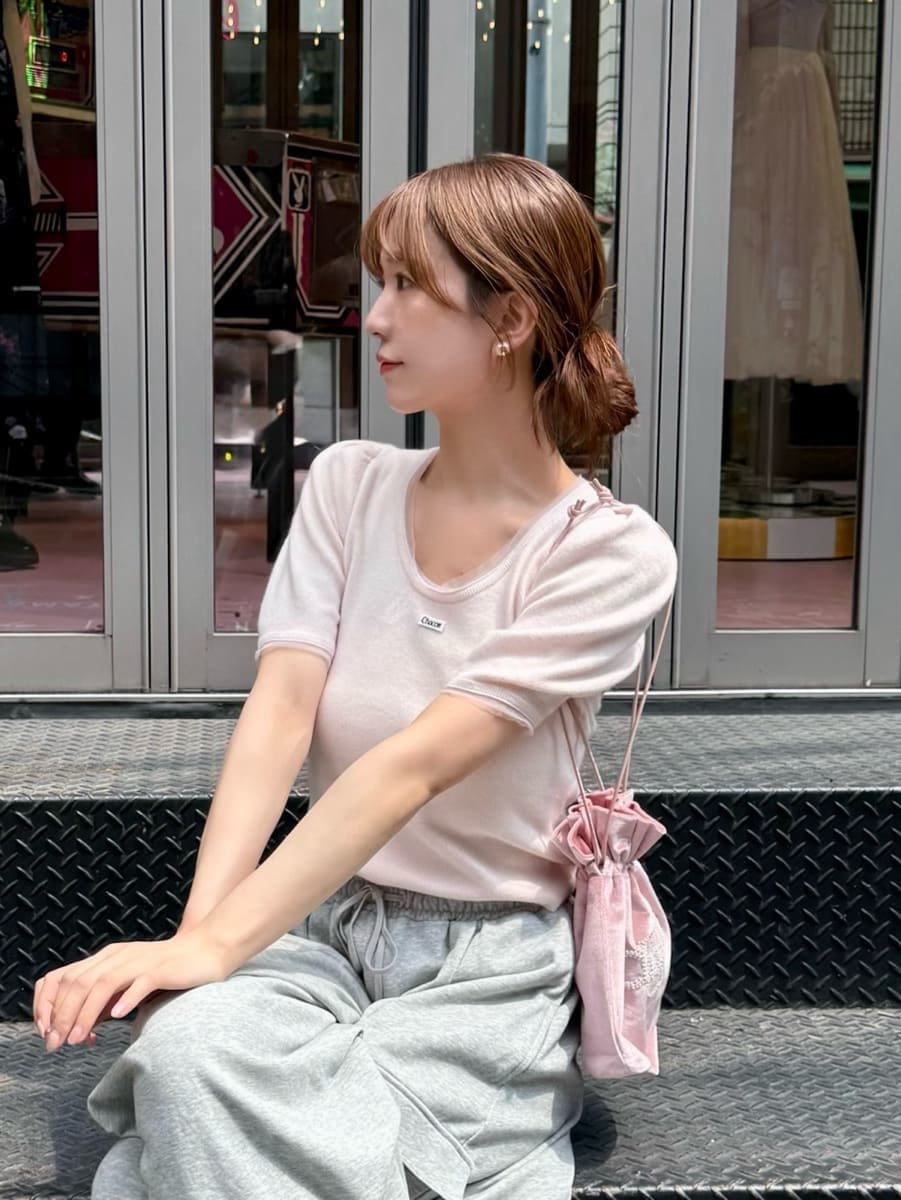 ピンク系のニット/セーター、グレー系のその他パンツ、ピンク系のハンドバッグを着用したレディースの夏コーディネートの5枚目の写真