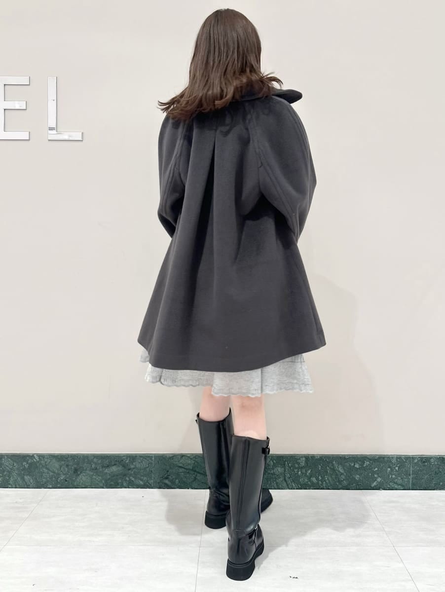 グレー系のステンカラーコート、ブラック系のブーツ、ブラック系のショルダーバッグを着用したレディースの秋コーディネートの4枚目の写真