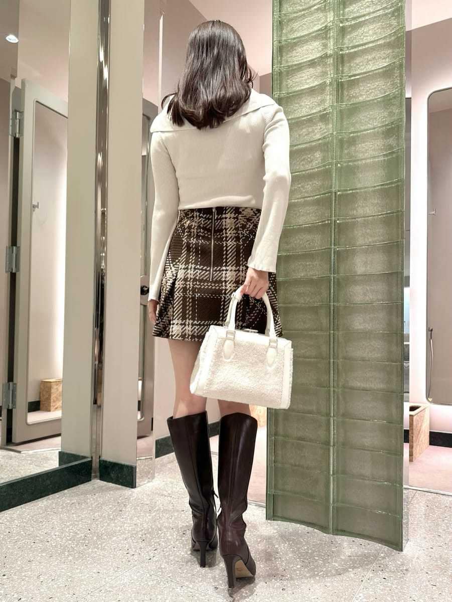 ホワイト系のニット/セーター、ブラウン系のスカート、ブラウン系のブーツを着用したレディースの秋コーディネートの4枚目の写真