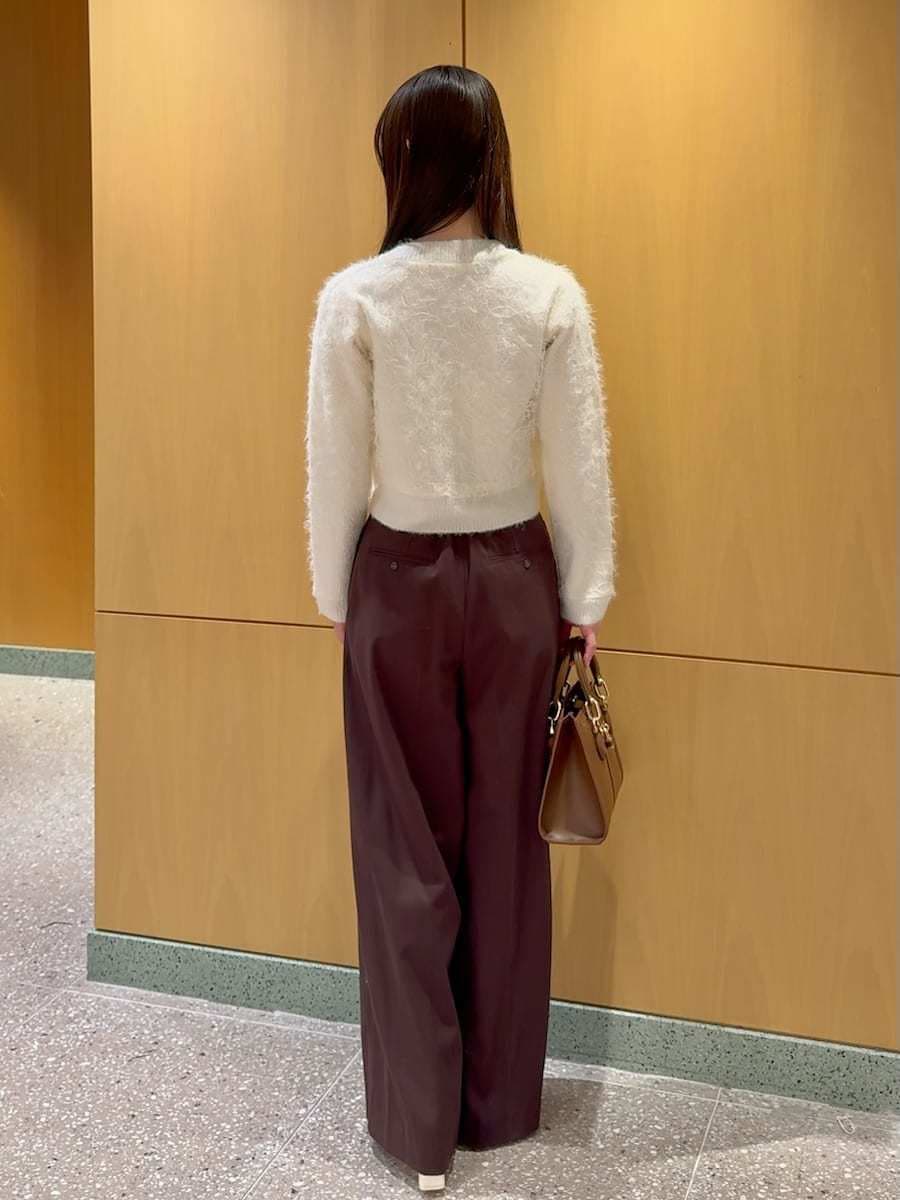 ブラウン系のスラックス、ホワイト系のカーディガン/ボレロ、ブラウン系のハンドバッグを着用したレディースの冬コーディネートの3枚目の写真