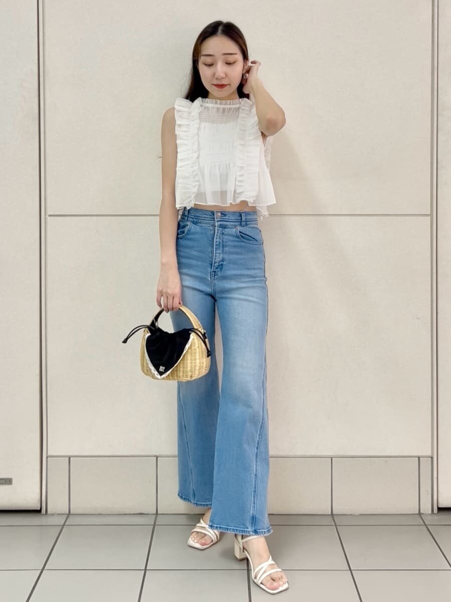 ブルー系のデニムパンツ、ブラック系のかごバッグ、ホワイト系のシャツ/ブラウスを着用したレディースの夏コーディネートの2枚目の写真