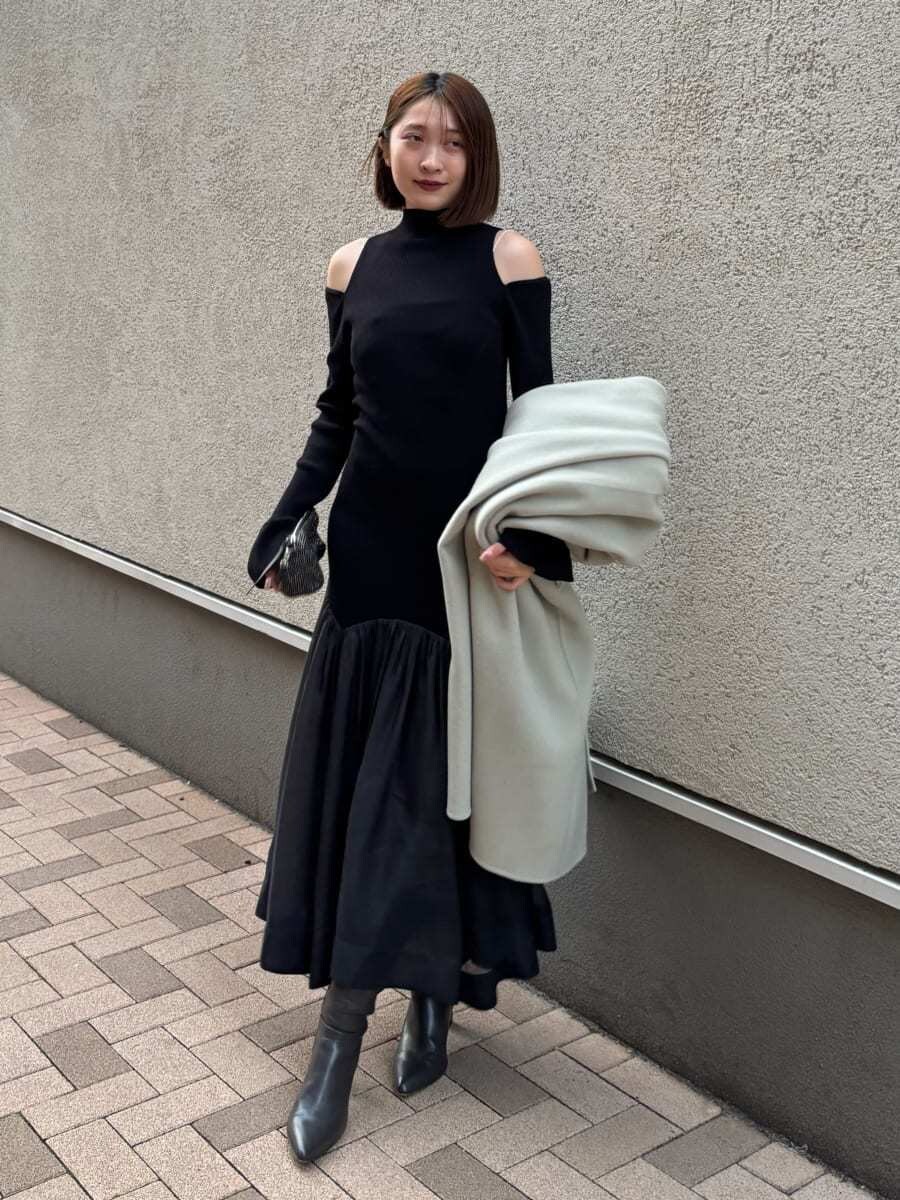 グレー系のブーツ、グリーン系のチェスターコート、ブラック系のワンピースを着用したレディースの秋コーディネートの7枚目の写真
