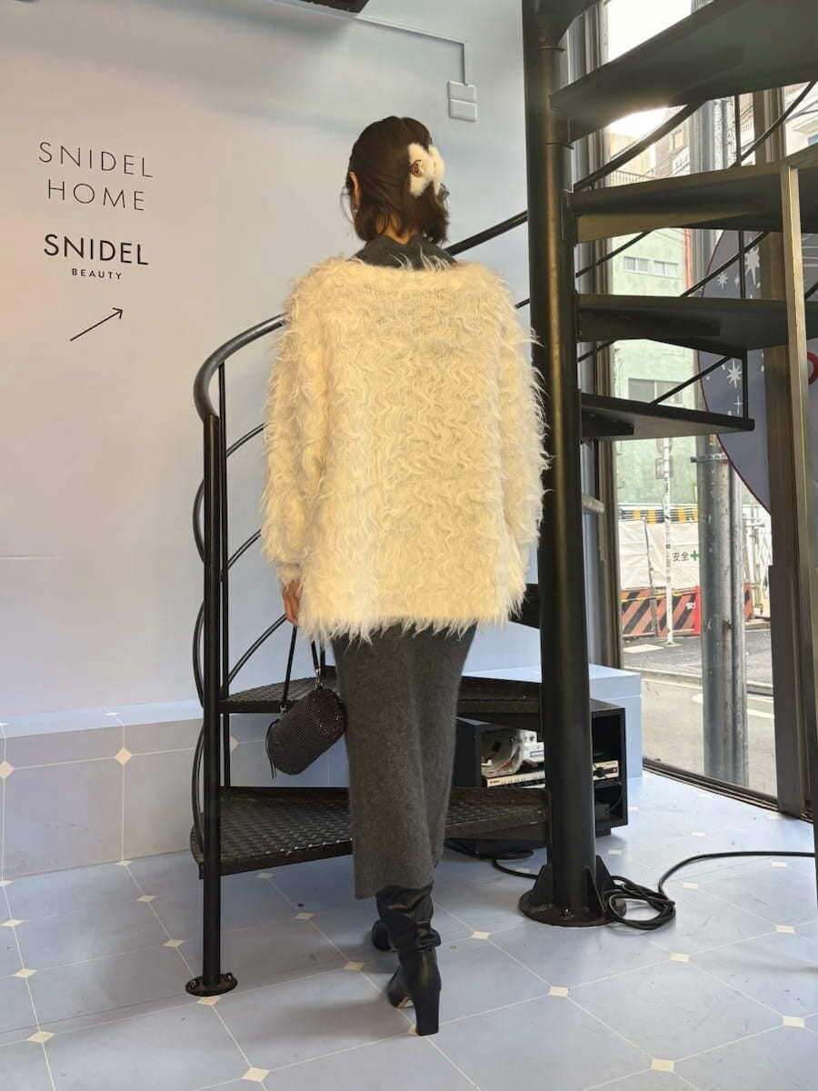 グレー系のワンピース、ホワイト系のカーディガン/ボレロを着用したレディースの冬コーディネートの3枚目の写真