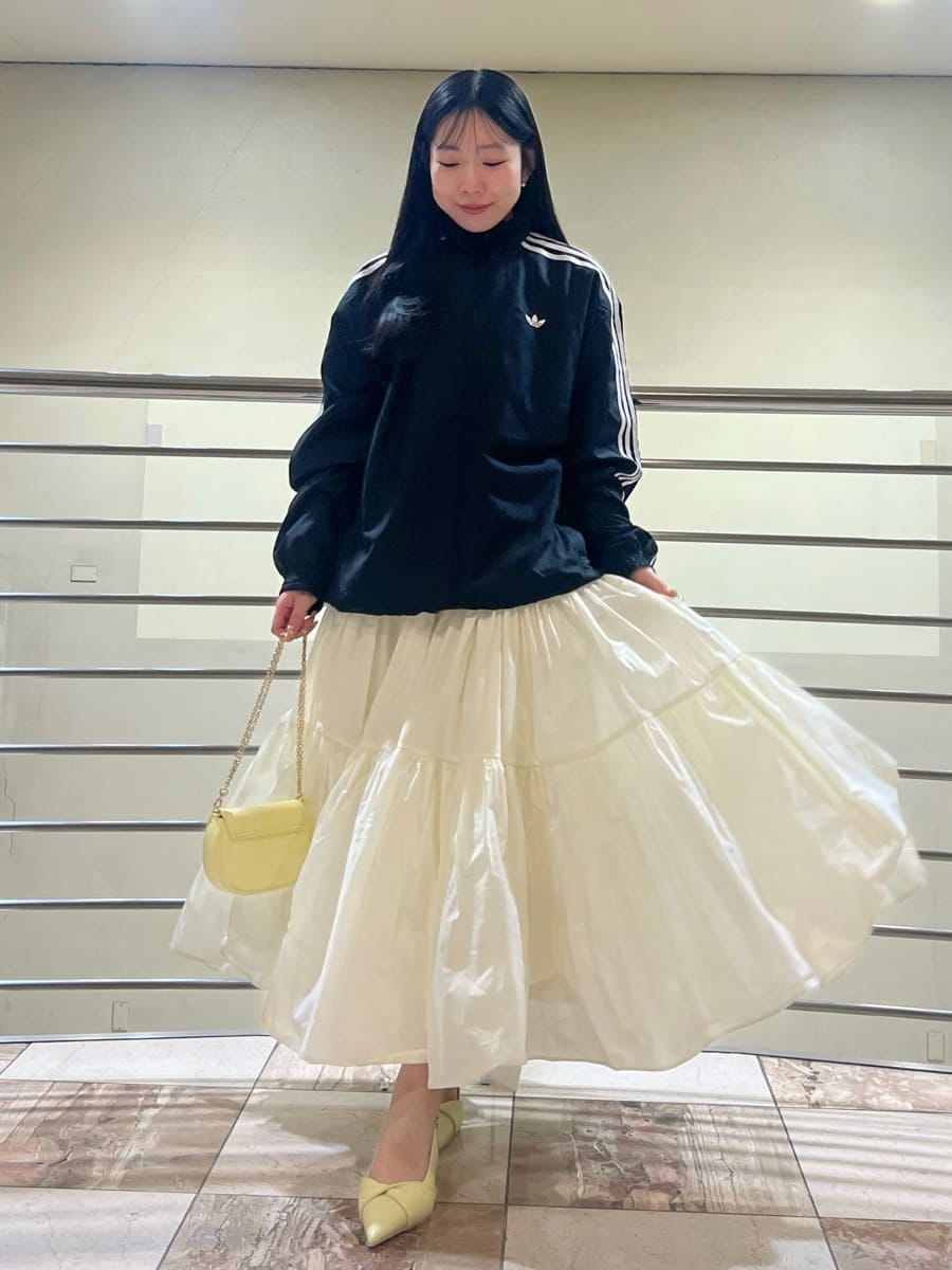 ホワイト系のスカート、ブラック系のブルゾン、イエロー系のパンプスを着用したレディースの春コーディネートの2枚目の写真