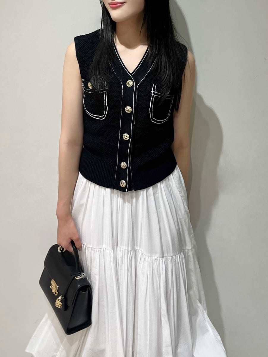 ブルー系のニット/セーター、ホワイト系のスカート、ブラック系のショルダーバッグを着用したレディースの夏コーディネートの3枚目の写真