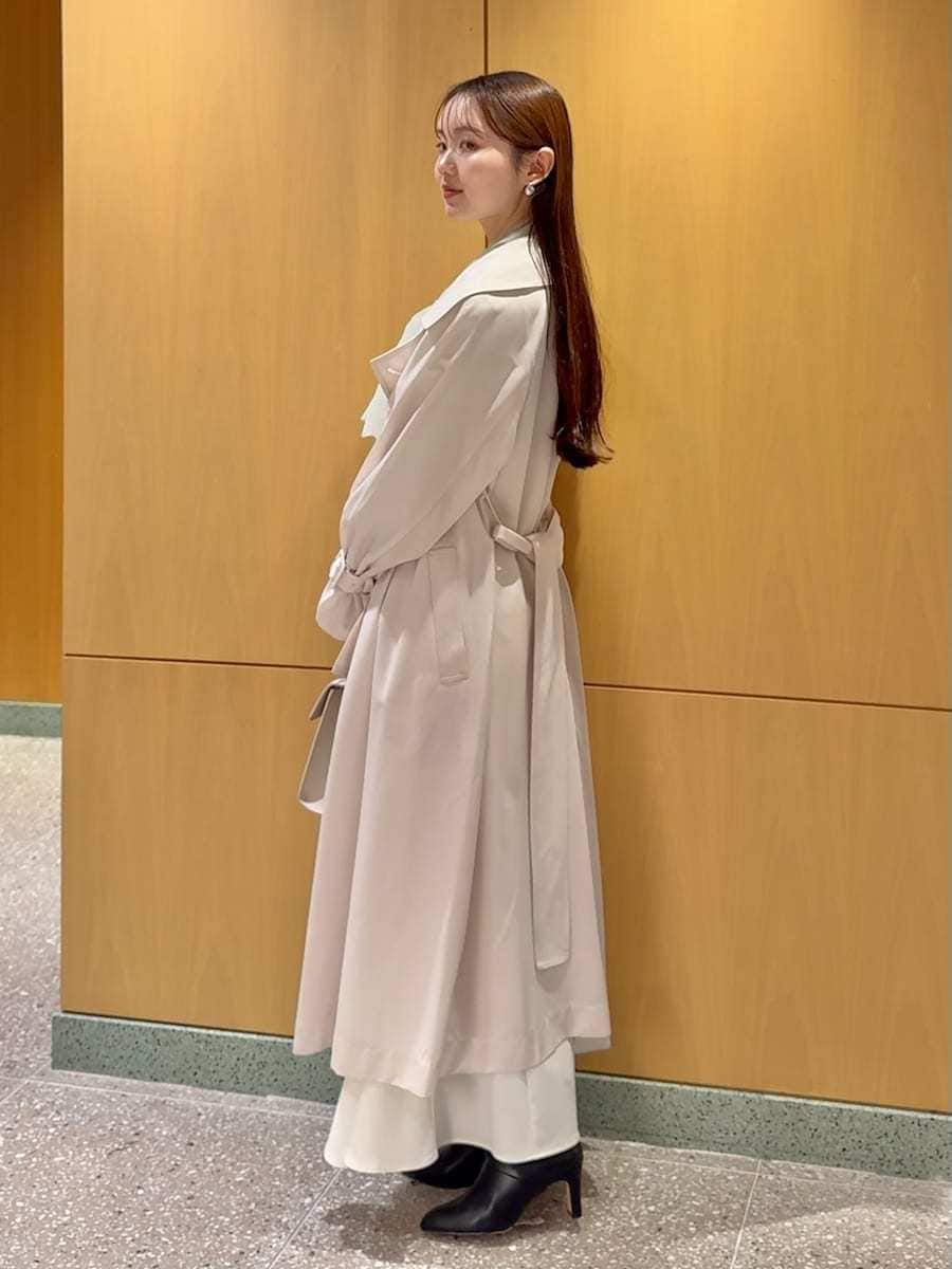 ブラック系のブーツ、ホワイト系のトレンチコート、ホワイト系のスカートを着用したレディースの冬コーディネートの2枚目の写真