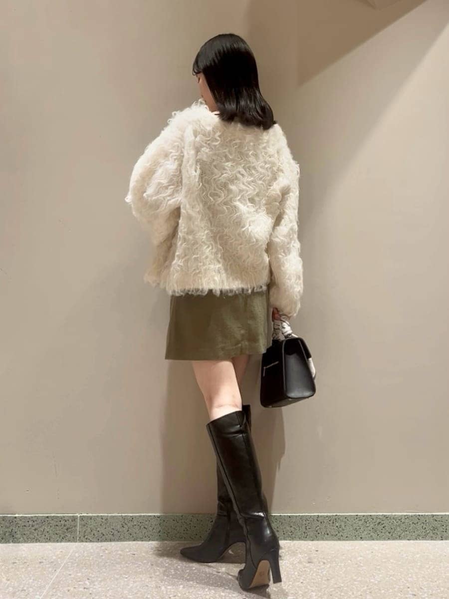 グリーン系のワンピース、ホワイト系のカーディガン/ボレロ、ブラック系のブーツを着用したレディースの秋コーディネートの3枚目の写真