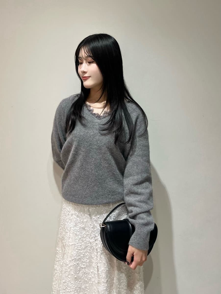 グレー系のニット/セーター、ホワイト系のスカート、ブラック系のハンドバッグを着用したレディースの秋コーディネートの3枚目の写真